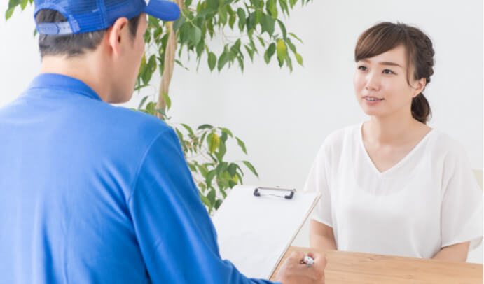 「引越し事業者に見積もりを出してもらう女性」