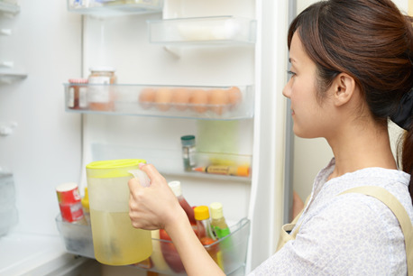 冷蔵庫に飲み物をしまう女性